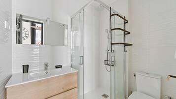 Une salle de bain moderne avec une douche à parois de verre, un meuble-lavabo en bois et un grand miroir.