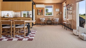 A modern kitchen with wooden cabinets, a dining area with a checkered rug, and a seating area with a view. - 5 Star Holiday Home in Brenderup Fyn (Middelfart)