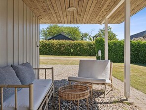 An outdoor seating area with a wooden pergola, a sofa, a chair, and a wicker table. - 5 Star Holiday Home in Brenderup Fyn (Middelfart)