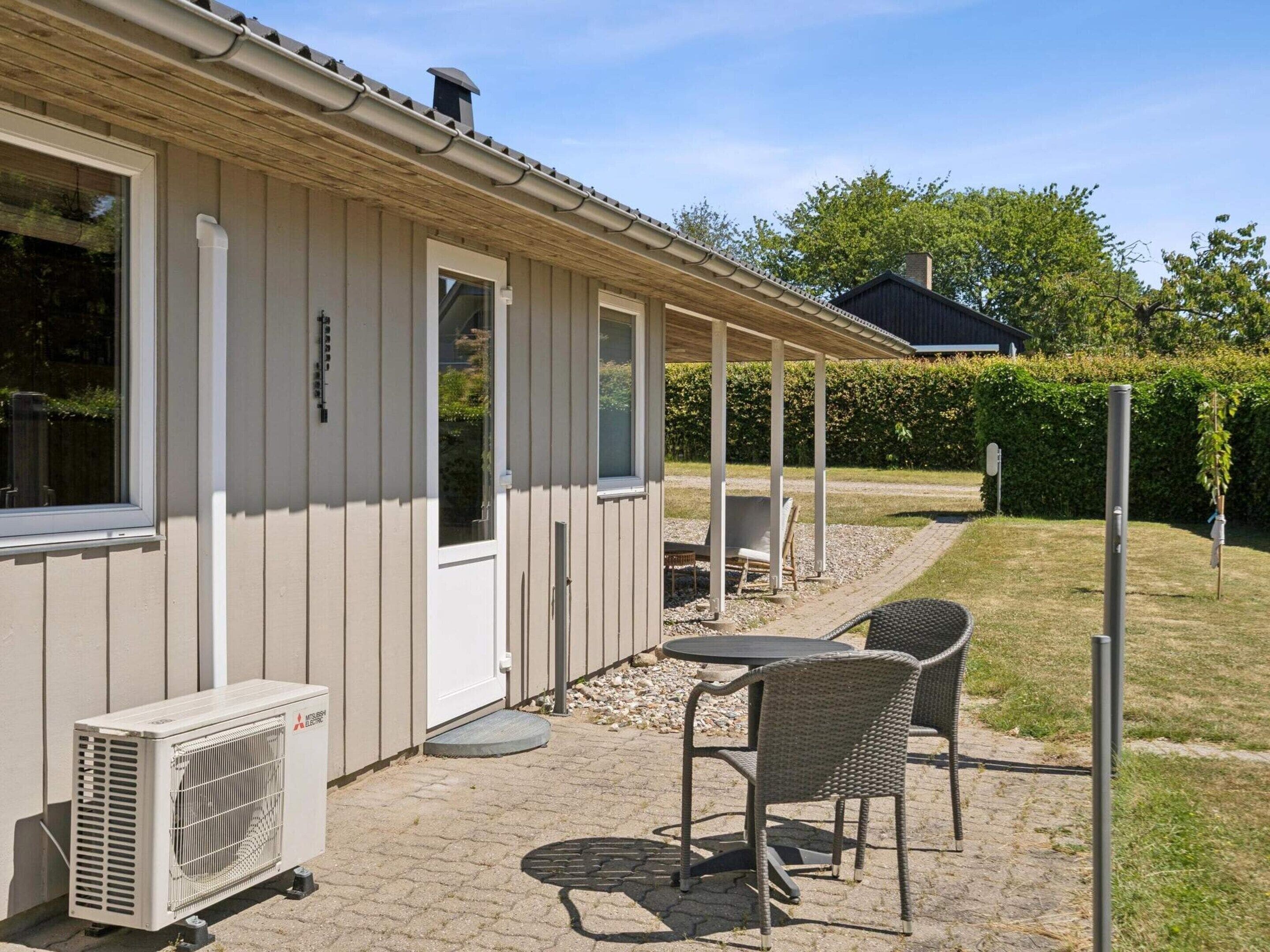 A building with a covered patio area, outdoor seating, and an air conditioning unit.