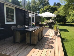 A deck with a dining table and chairs, a covered seating area, and a potted plant. - 5 Star Holiday Home in Nykobing Sj (Nykobing Sjaelland)