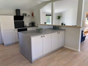 Eine moderne Küche mit einer zentralen Kochinsel, weißen Schränken und Holzboden.