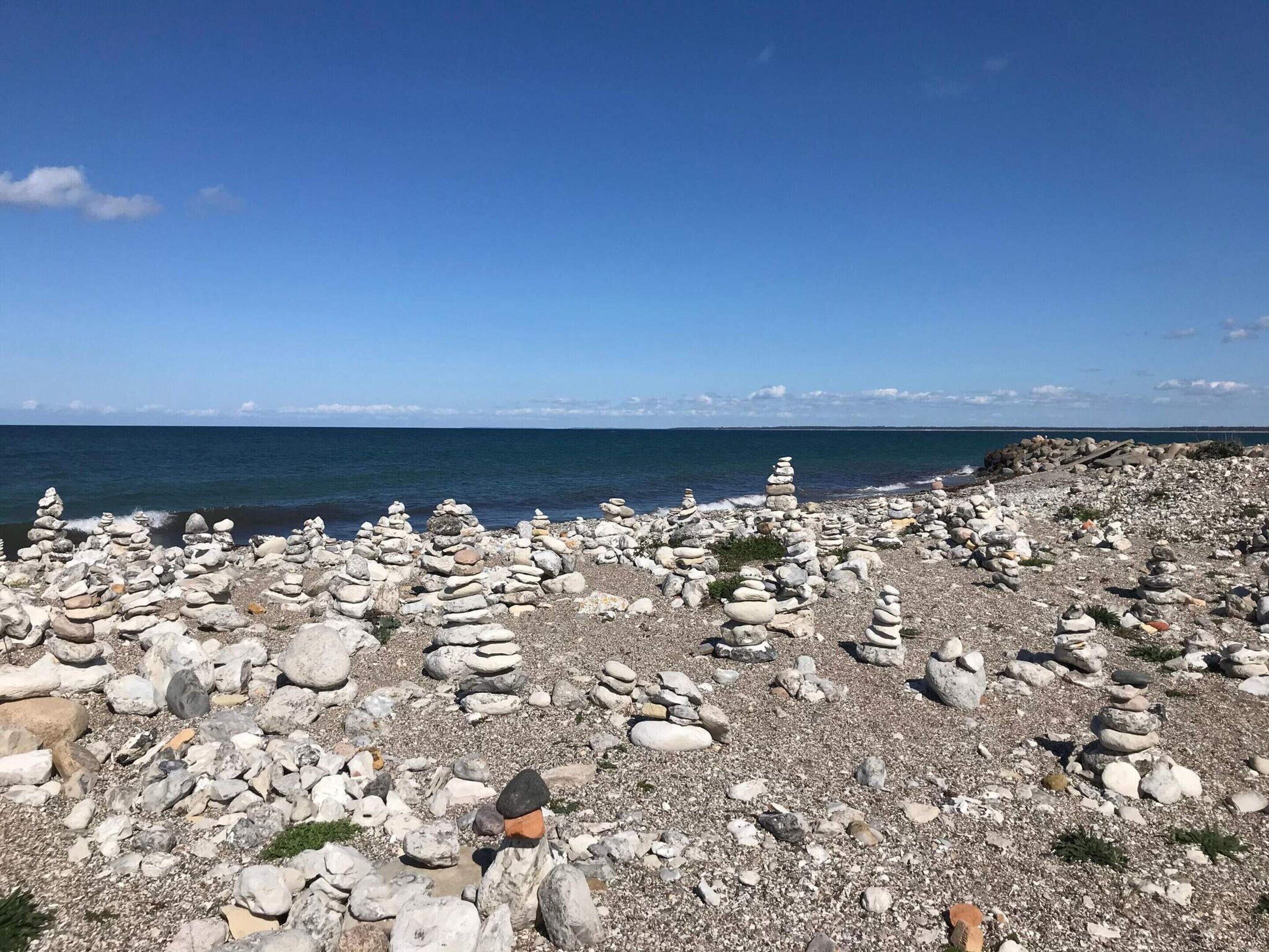 A rocky beach with stacks of stones and a clear view of the ocean.