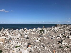 A rocky beach with stacks of stones and a clear view of the ocean. - 5 Star Holiday Home in Nykobing Sj (Nykobing Sjaelland)