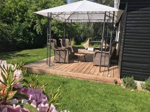 Eine Terrasse im Freien mit Korbmöbeln, einem Tisch und einem Sonnensegel.