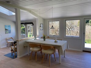 Ein Essbereich mit einem Tisch für vier Personen, Holzkstühle, einem Fenster mit Blick auf Bäume und einem Oberlicht.