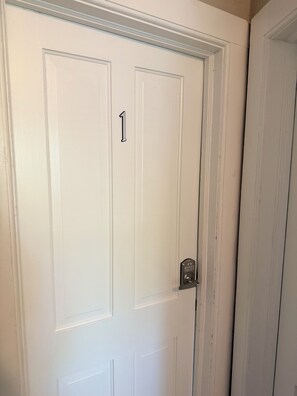 En vit dörr med ett handtag som har siffran 1 och ett nyckelhål.