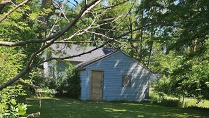 Ein eingezäunter Garten mit einer kleinen Gartenhütte und einem Haus im Hintergrund.