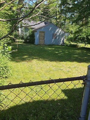 A fenced yard with a small shed and a house in the background. - Cozy Home close to Notre Dame & Downtown Southbend (South Bend)