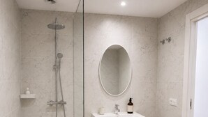 A modern bathroom with a walk-in shower, a vanity with a mirror, and a wooden floor. - El Paraíso Apartment - Downtown Marbella - Free Parking (Marbella)