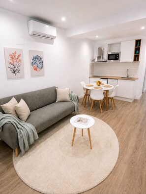 A modern living room with a grey sofa, a round coffee table, and a dining area with a white table and chairs. - El Paraíso Apartment - Downtown Marbella - Free Parking (Marbella)