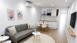 A modern living room with a grey sofa, a round coffee table, and a dining area with white chairs. - El Paraíso Apartment - Downtown Marbella - Free Parking (Marbella)