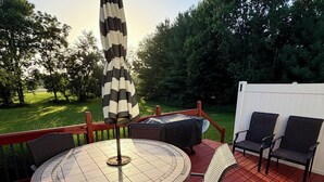 Eine Terrasse mit einem runden Tisch, Stühlen und einem Sonnenschirm.