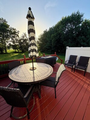 Eine Terrasse mit einem runden Tisch, Stühlen und einem Sonnenschirm.