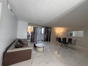 Ein modernes Wohnzimmer mit einer Couch, einem Couchtisch und einem Essbereich mit Stühlen und einem Tisch.