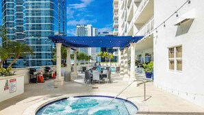 A rooftop pool area with a hot tub, outdoor seating, and a view of surrounding high-rise buildings. - Brickell Penthouse Breathtaking Views (Miami)