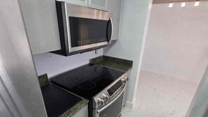 A compact kitchen with a built-in microwave, oven, and stovetop. - Brickell Penthouse Breathtaking Views (Miami)