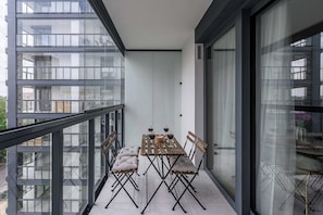 A balcony with a table and chairs, a view of the cityscape, and a glass door. - New House With Pool Near Beach (Warsaw)