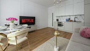 A modern living room with a dining area, a kitchen, and a television displaying 'NETFLIX'. - New House With Pool Near Beach (Warsaw)