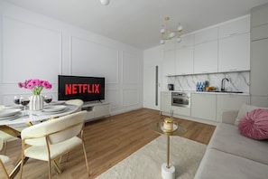 A modern living room with a dining area, a kitchen, and a television displaying 'NETFLIX'. - New House With Pool Near Beach (Warsaw)