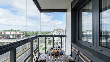 Ein Balkon mit einem Tisch für zwei Personen, einem Glas Rotwein und einer Obstschale.