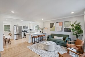 A modern kitchen with white cabinetry, stainless steel appliances, and a central island with stools. - Luxury Stay with Hot Tub, Fire Pit and Games (Charlotte)