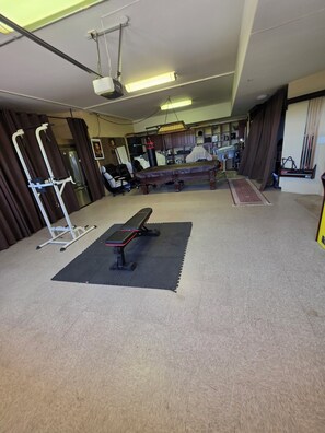 Ein Fitnessraum mit Trainingsgeräten, einer Bank und einem Schlagbeutel.