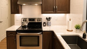 Une cuisine moderne avec des meubles de rangement en bois foncé, une cuisinière en acier inoxydable et un plan de travail en marbre.