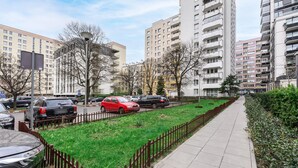 A residential area with multi-story apartment buildings, a sidewalk, and a green space with a fence. - City Apartment in Warsaw (Warsaw)