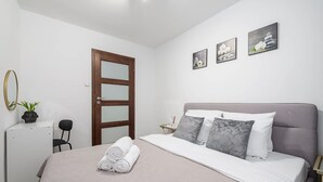 A bedroom with a bed, a door, a chair, and wall art. - City Apartment in Warsaw (Warsaw)