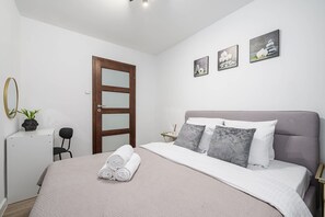 Ein Schlafzimmer mit Bett, Tür, Stuhl und Wandbildern.