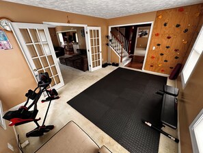 A home gym with exercise equipment, a climbing wall, and a staircase leading to another level. - Fountain House- Spacious Okemos home in nature with comforts near MSU (Okemos)