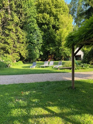 Jardí amb una glorieta, un camí de grava i quatre seients de relaxació.