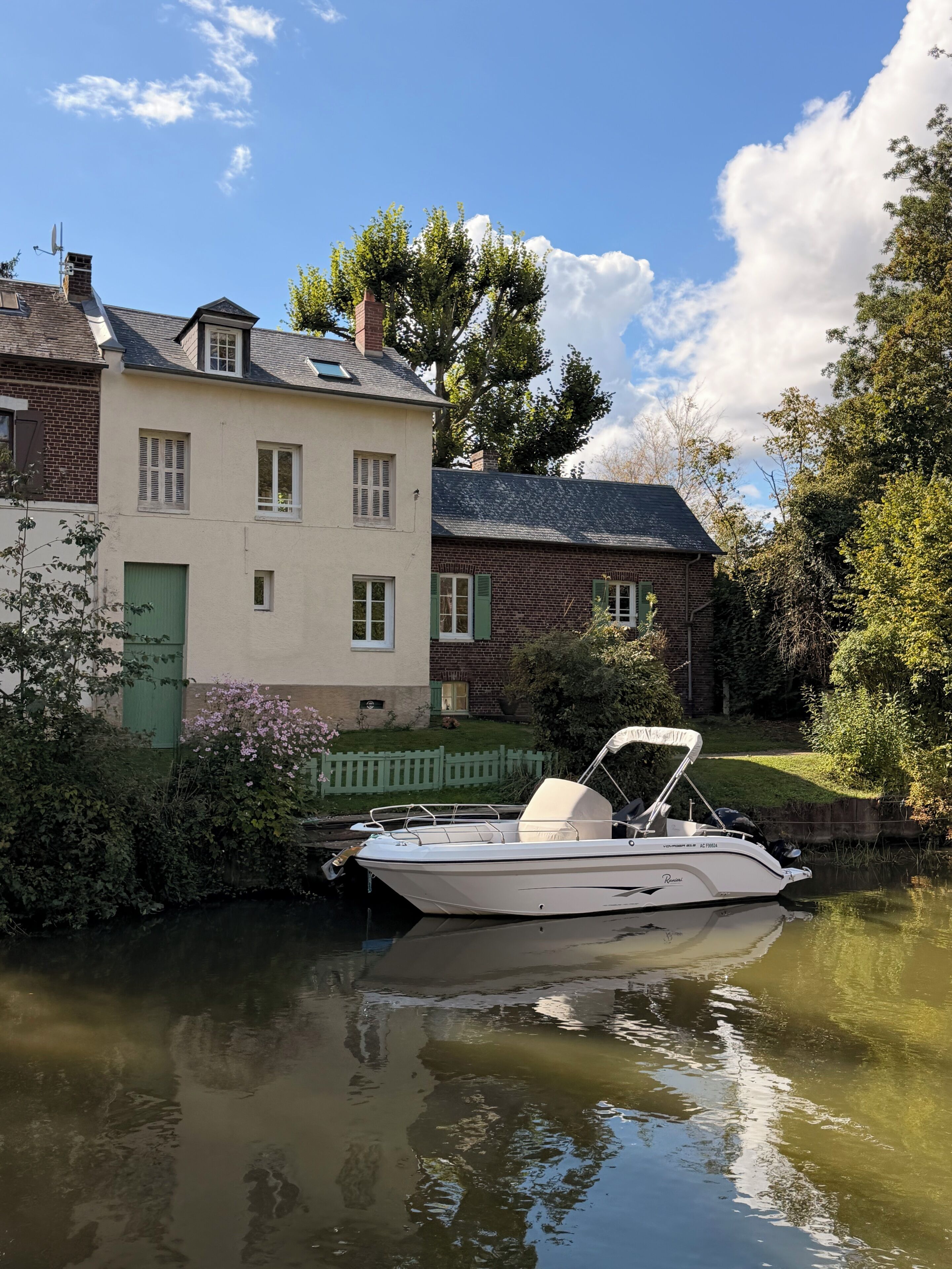 A boat docked at a calm river with a house beside it.