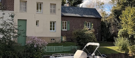 A boat docked at a calm river with a house beside it.