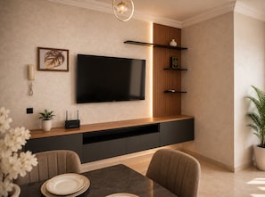 Ein modernes Wohnzimmer mit einem flachbildfernseher, der an einer Holzwand angebracht ist, einem integrierten Unterhaltungsmöbel darunter und einem Essbereich mit Tisch und Stühlen.