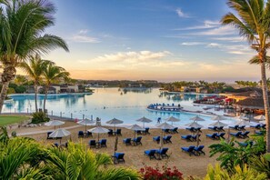 Et resort med flere swimmingpools, solstole og palmer.