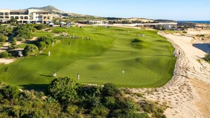 A golf course with a clubhouse, a mountain in the background, and a clear sky. - Luxury 4BR Villa | Pool, Jacuzzi & Golf Views (Cabo San Lucas)