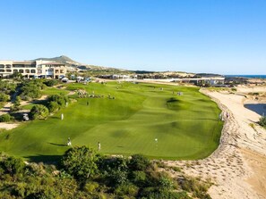 A golf course with a clubhouse, a mountain in the background, and a clear sky. - Luxury 4BR Villa | Pool, Jacuzzi & Golf Views (Cabo San Lucas)