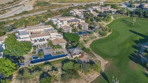 An aerial view of a residential area with multiple houses, a swimming pool, and a golf course. - Luxury 4BR Villa | Pool, Jacuzzi & Golf Views (Cabo San Lucas)