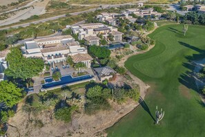 An aerial view of a residential area with multiple houses, a swimming pool, and a golf course. - Luxury 4BR Villa | Pool, Jacuzzi & Golf Views (Cabo San Lucas)