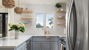 Une cuisine moderne dotée d’un grand îlot central, de meubles gris et d’un réfrigérateur en acier inoxydable.