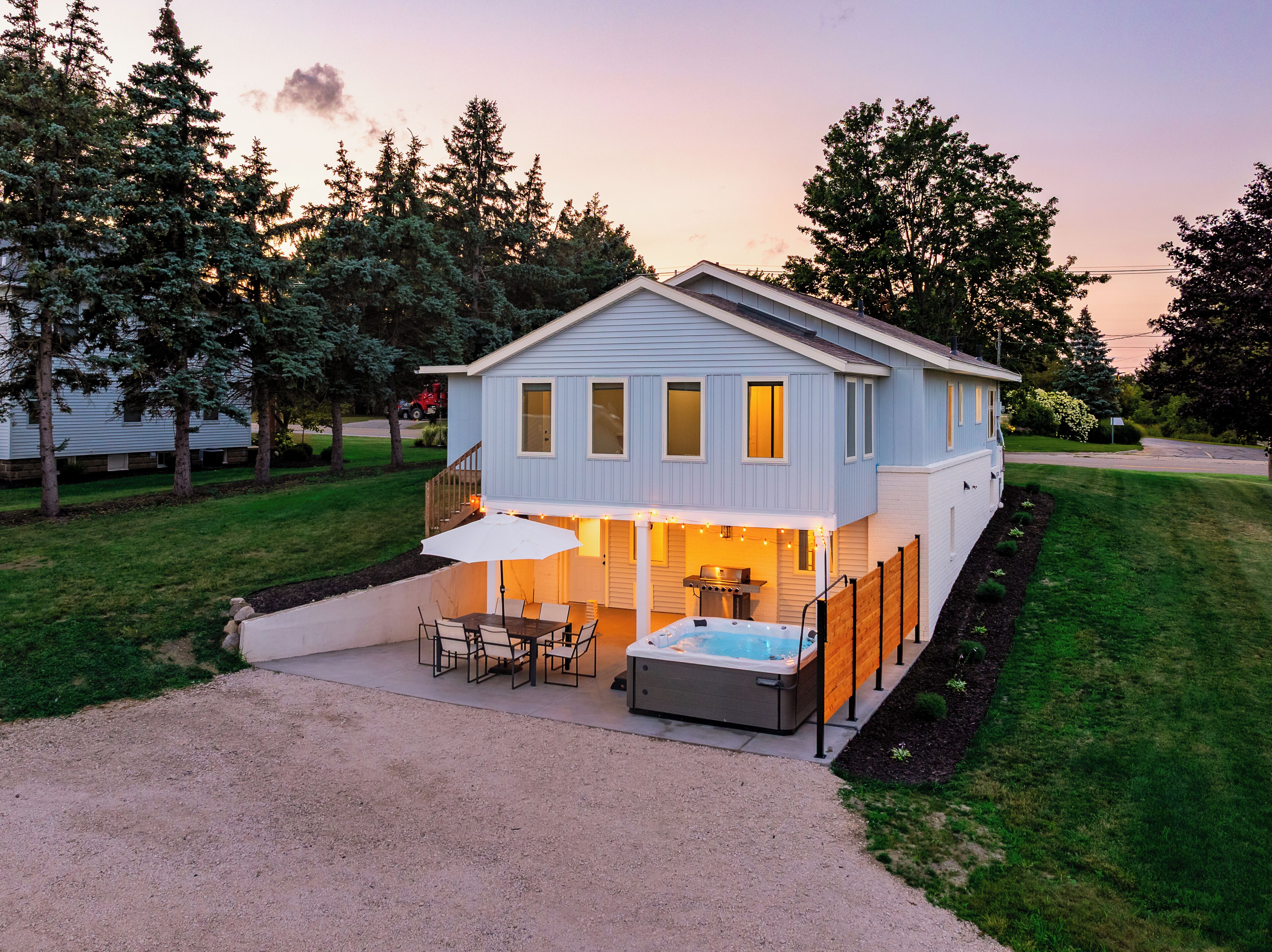 A two-story house with a patio area, outdoor seating, and a hot tub.