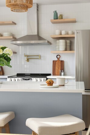 A kitchen with a central island, white cabinetry, and a stainless steel range hood.