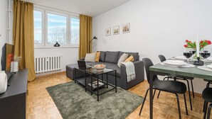 A modern living room with a sofa, coffee table, and dining table set for two. - Magnificent Beach House for 6 (Warsaw)