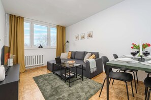 Ein modernes Wohnzimmer mit Sofa, Couchtisch und Esstisch für zwei Personen.