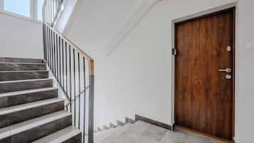 Eine Treppe mit einem Holnänder und einer Holztür mit Griff und Schloss.