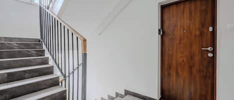 A staircase with a wooden handrail and a wooden door with a handle and lock.