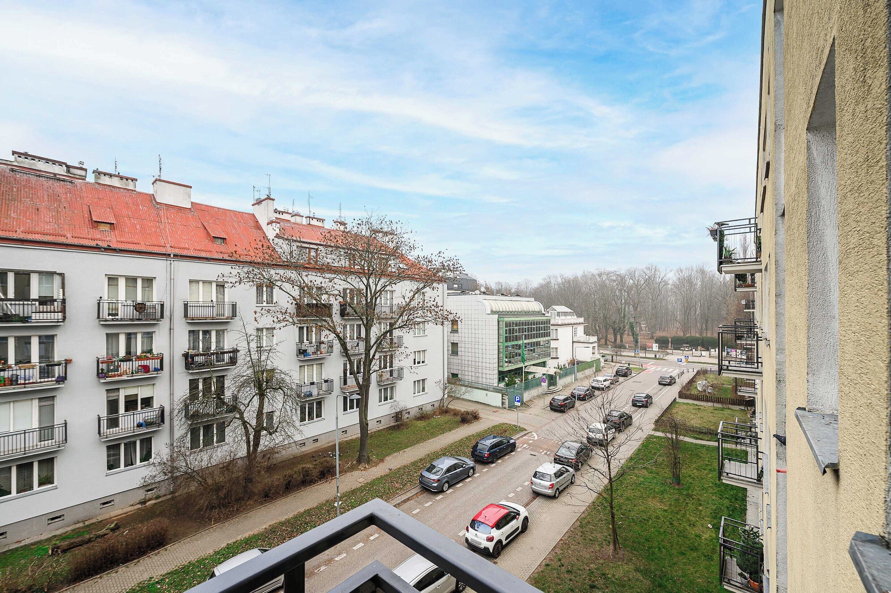 Uma área residencial com edifícios altos, uma rua com carros estacionados e céu aberto.