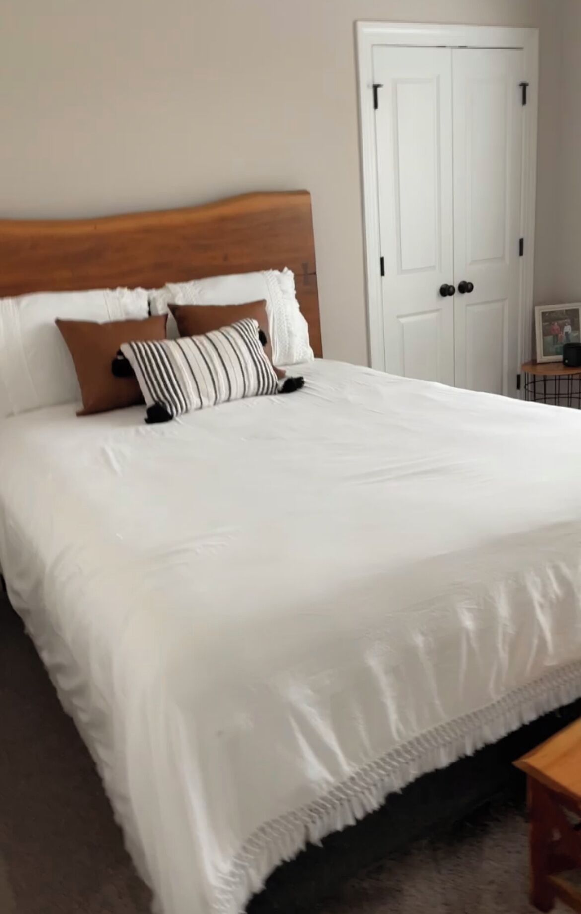 A neatly made bed with a wooden headboard, white bedding, and a few decorative pillows.